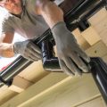Worker Installing Gutter System on Roof